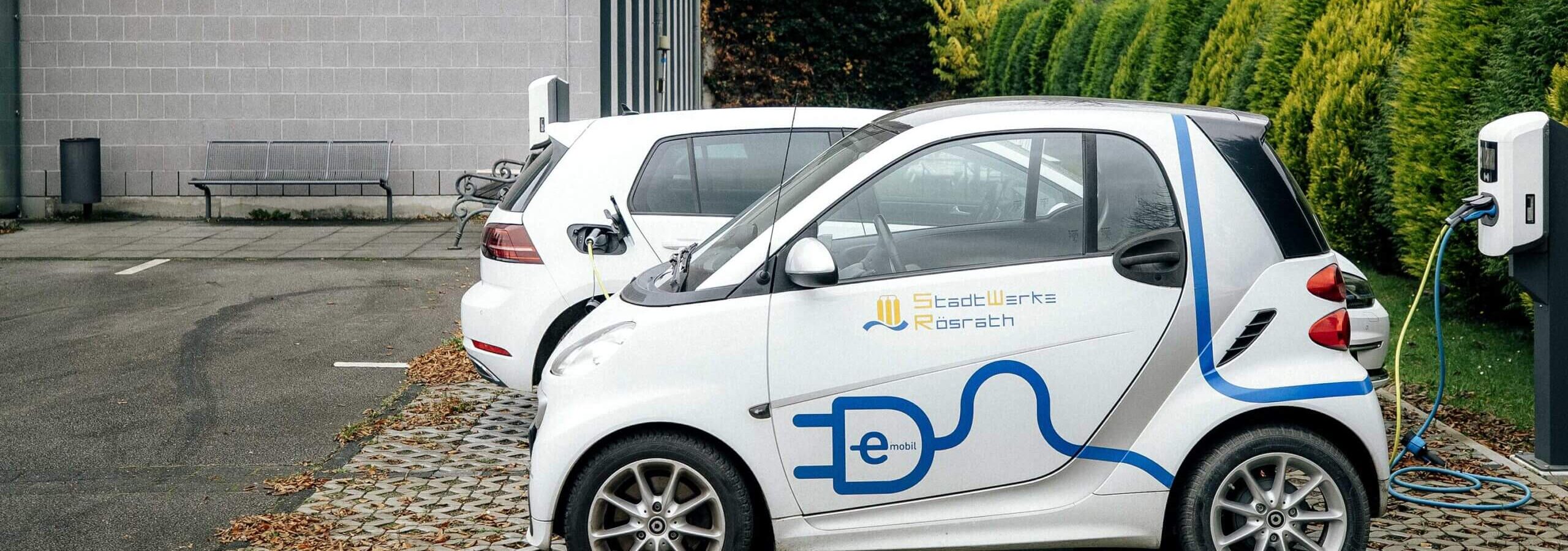 Ein Elektrofahrzeug der StadtWerke Rösrath lädt an der Ladestation auf dem Parkplatz vor dem Firmengebäude