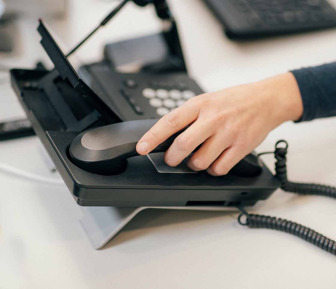 Die Hand einer Mitarbeiterin aus dem Kundenzentrum der StadtWerke Rösrath hebt den Telefonnummer auf