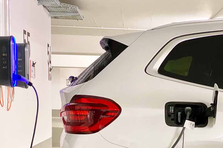 Ein weißes Elektroauto lädt in einer Tiefgarage an einer Ladestation