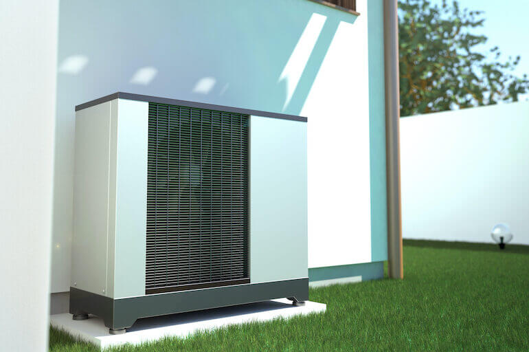 Eine Wärmepumpe an einer Hauswand in einem Garten