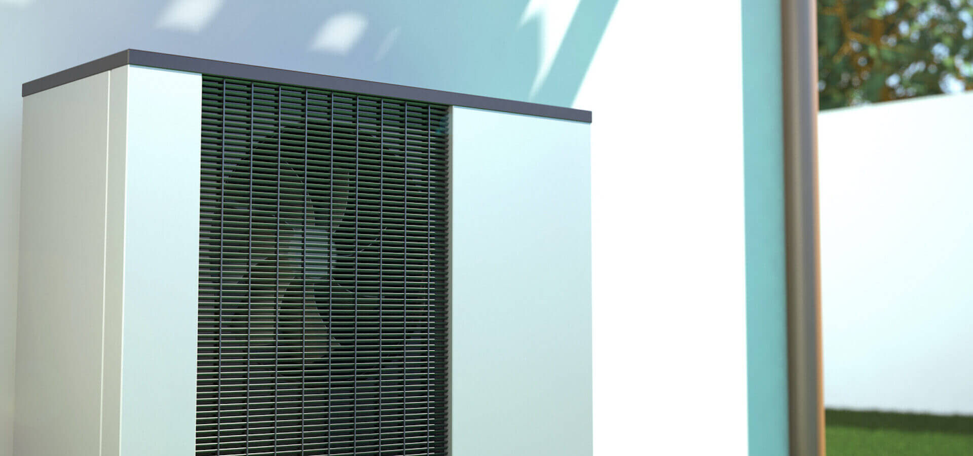 Eine Wärmepumpe an einer Hauswand im Garten