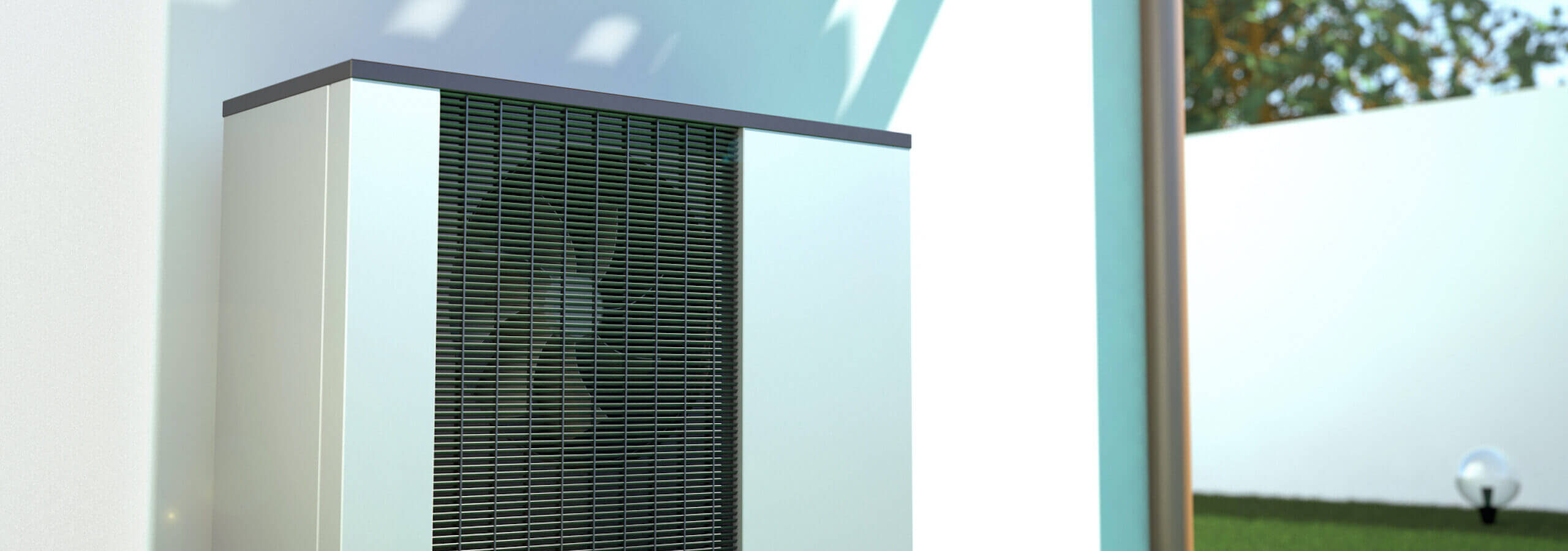 Eine Wärmepumpe an einer Hauswand im Garten