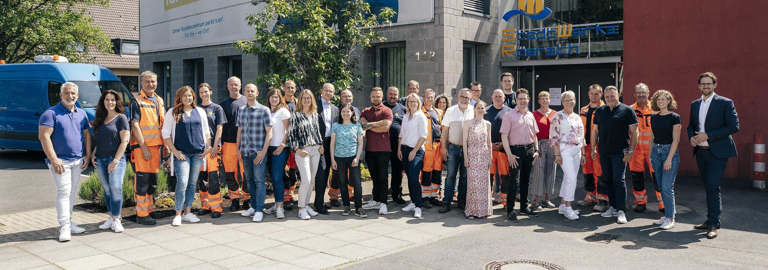 Das Team der StadtWerke Rösrath steht versammelt vor dem Eingang des Firmengebäudes in Rösrath