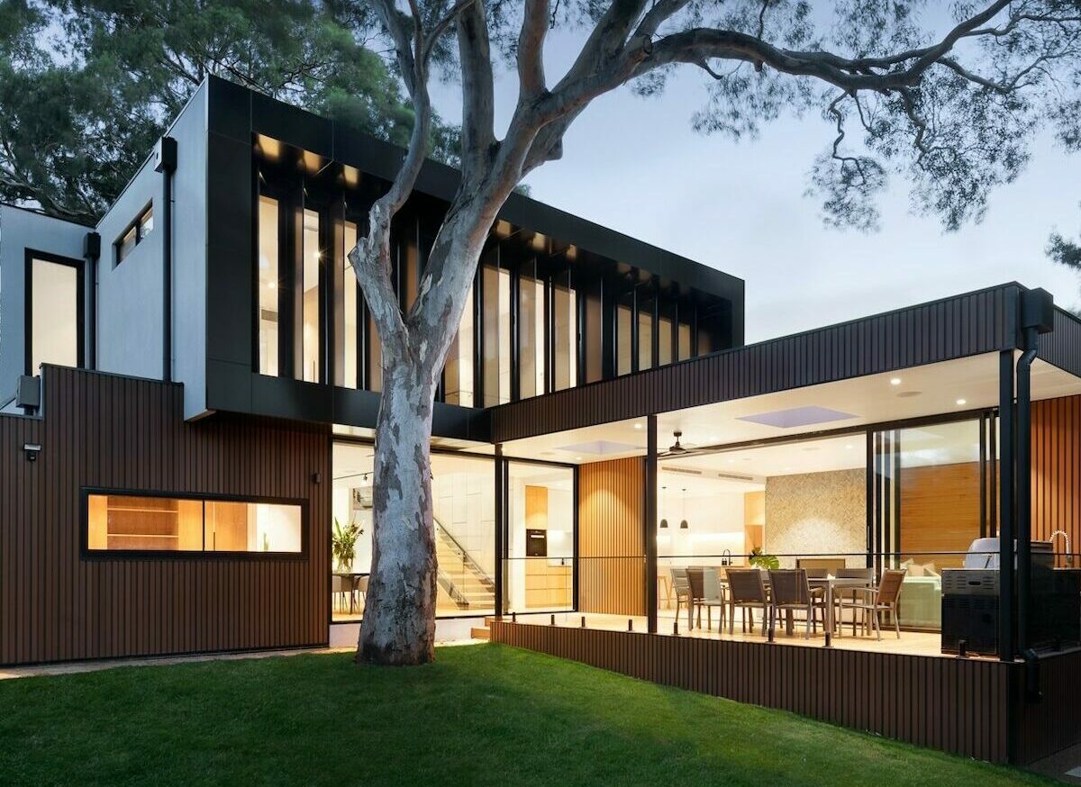 Ein großes Einfamilienhaus in der Abenddämmerung, in dem Licht brennt.